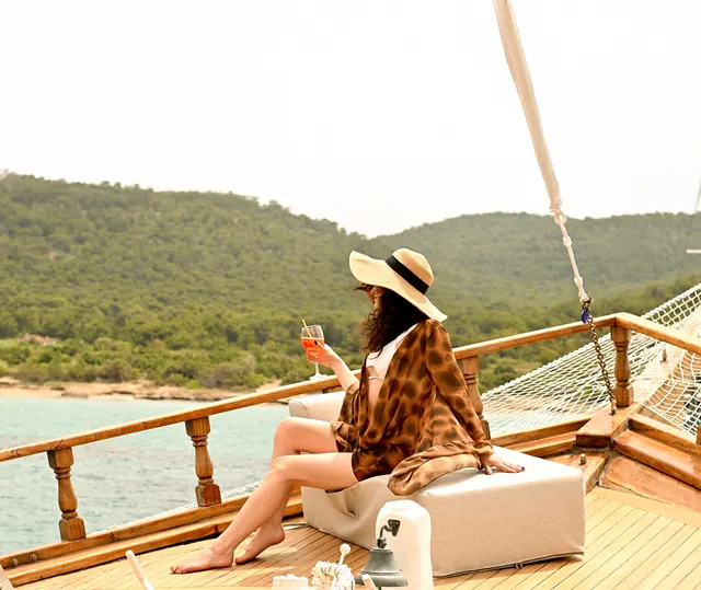 Relaxing on deck beside a pine-covered coast